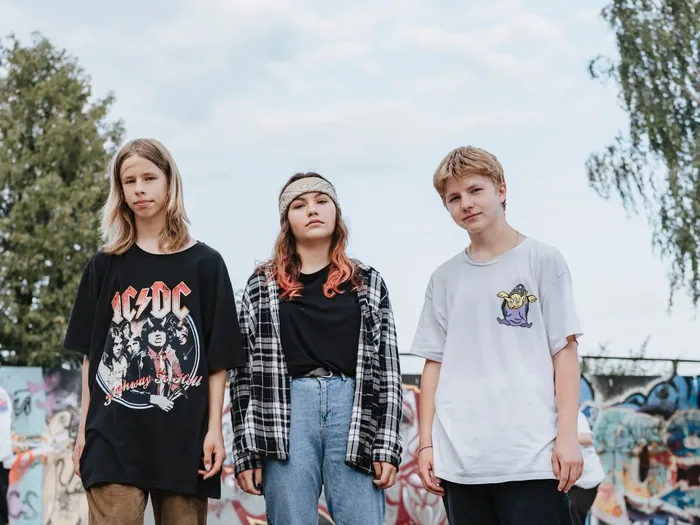 Tres adolescentes de pie al aire libre en un espacio urbano