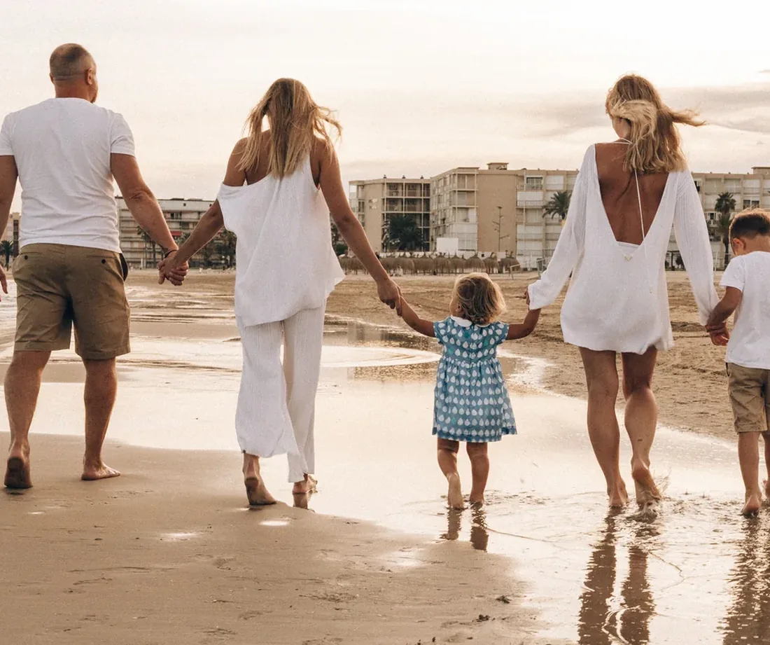 Familia caminando junta hacia el horizonte al atardecer, tomados de la mano